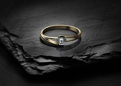 Un anello d'oro con il cristallo, appoggiato sul ardesia nera. Foto realizzata con la tecnica della pittura con la luce. Misterioso. Orizzontale