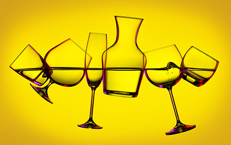 Composizione dei bicchieri differenti sullo sfondo giallo. I bicchieri sono inclinati, riempiti d'acqua e allineati al livello dell'acqua.
