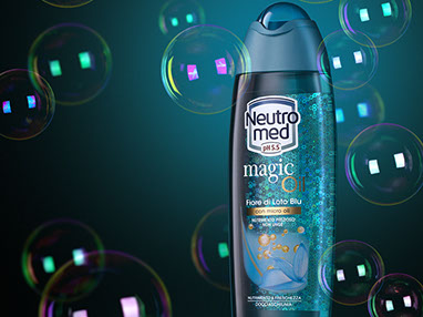 La bottiglia blu di bagnoschiuma Neutro Med Magic Oil, con le bolle di sapone intorno. Sfondo blu, clima misterioso. Orizzontale.