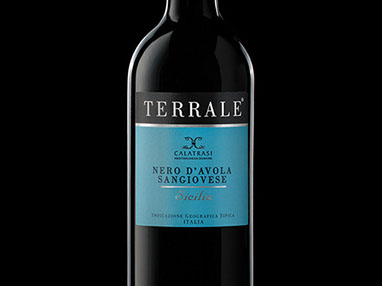 Una bottiglia nera di vino Terrale con etichetta azzurra. Sulla base a sinistra tre biglie: due nere e una. Sfondo nero.
