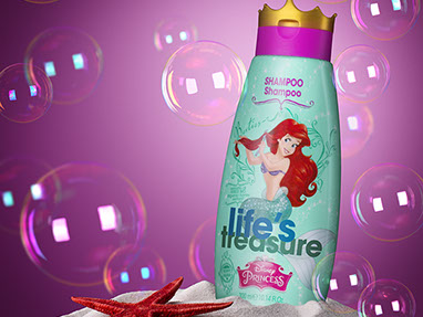 Bottiglia di shampoo per le bambine posizionata nella sabbia. Stella marina rossa sulla sinistra. Bolle di sapone intorno. Sfondo rosa scuro.