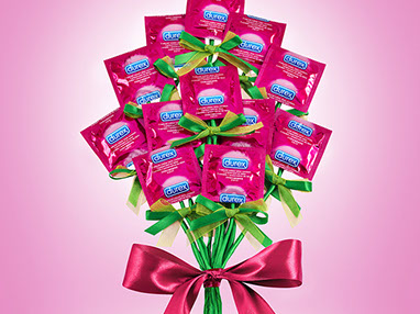 A bouquet of flowers created with pink wrapped Durex condoms. Big pink bow on the stems. Rose background. Funny and ironic.