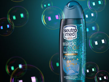 The blue bottle of Neutral Med Magic Oil shower gel, with soap bubbles around. Blue background, mysterious atmosphere. Horizontal.