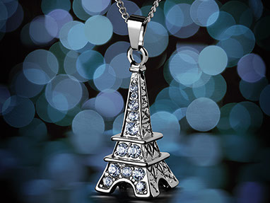 A pendant in the shape of the Eiffel Tower with blue crystals. With the chain. Dark background with blue and light blue bokeh. Vertical.